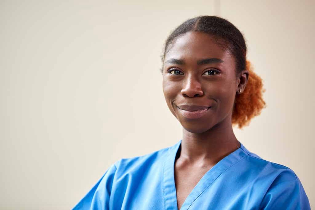 Portrait Of Smiling Female Nurse Or Doctor Wearing Scrubs